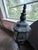 A classic heavy cast-iron wall lantern sconce with a round faceted glass globe and elaborate scrollwork mounting bracket....