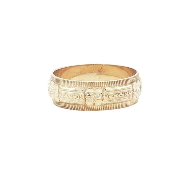 A mid-century 14k gold 6mm wide wedding ring with intricate engravings. The band features a detailed pattern with textured...