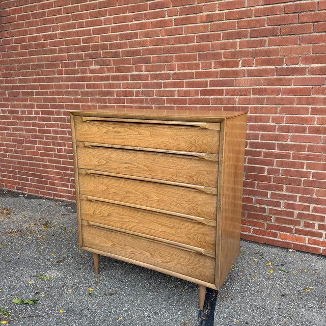 This mid-century modern walnut chest features five spacious drawers with sculpted integrated drawer pulls that create a...