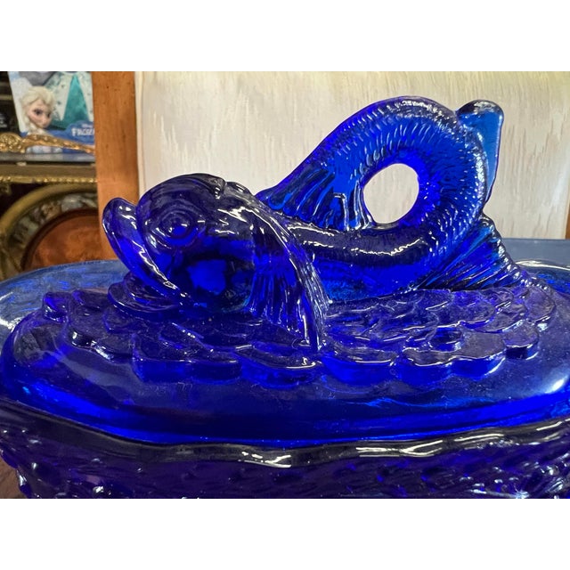 Wow what a piece to use on your table display. This item is a vintage cobalt blue glass covered dish featuring a fish...