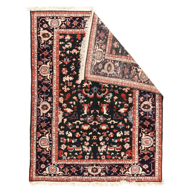 The navy border shows somewhat irregular, rotund turtle palmettes in the Heriz style. It frames the near black field with...