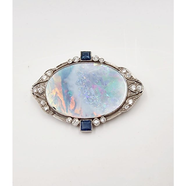 Splendid Italian-made brooch from the mid-20th century in 18Kt white gold with a central multicolored opal surrounded by...