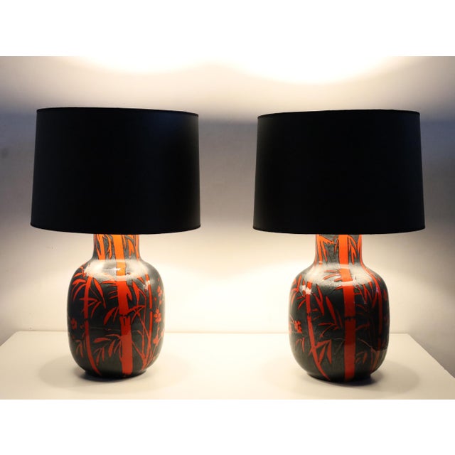 Beautiful pair of ceramic lamps with a bright red glazed bamboo design on a mottled glazed black metallic background. By...