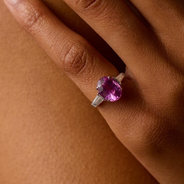 This elegant Mid Century ring centers on a captivating 4.34 carat oval cut pink sapphire, certified by AGL #8086750,...