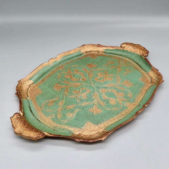 A classic vintage Florentine tray in turquoise and gold, with an ornate hand-painted scroll and floral motif across the...