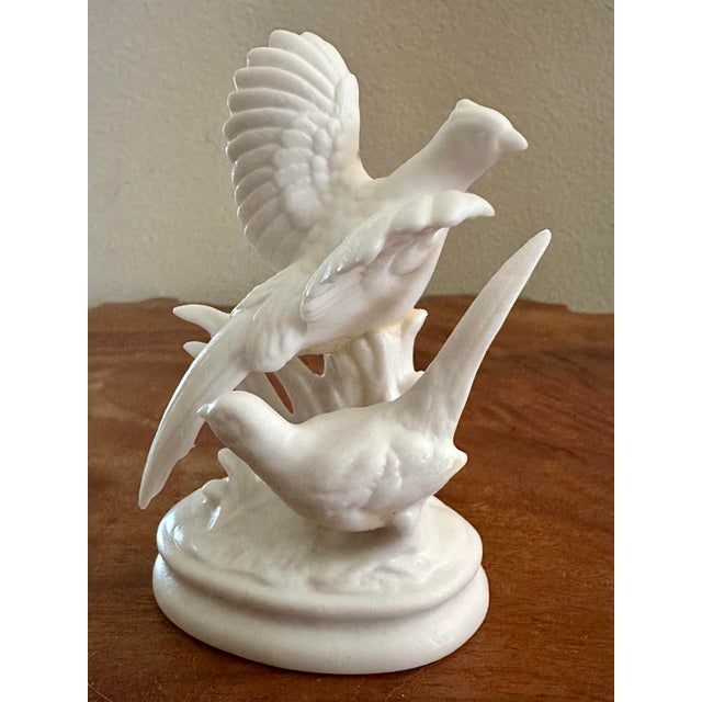 Vintage white bisque porcelain figurine of a pair of pheasants positioned together on a base with one bird displaying...