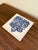 A classic Dutch Delft-style hand painted blue and white porcelain tile featuring an intricately rendered heraldic coat of...