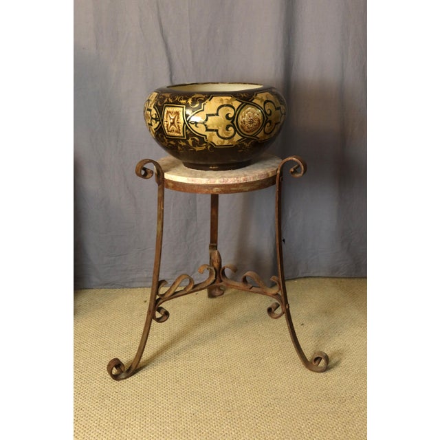 Wrought iron tripod stand with marble top. Early 20th century. DIMENSIONS: 0.78m high, 0.80m wide base, and 0.45m diameter...