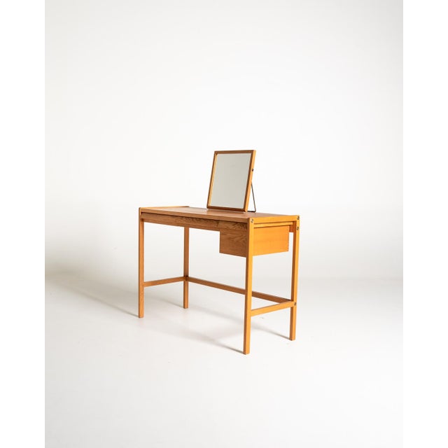 Oak vanity with a light profile, featuring a swivel mirror and three integrated storage compartments beneath the top....