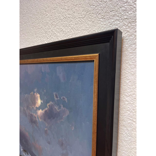 This oil on panel depicts a serene night scene by the beach, where gentle waves crash against rocky outcrops under a moody...