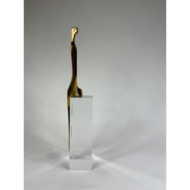 A bronze modern sculpture of person sat on a lucite block. Add a graceful statement to your space.
