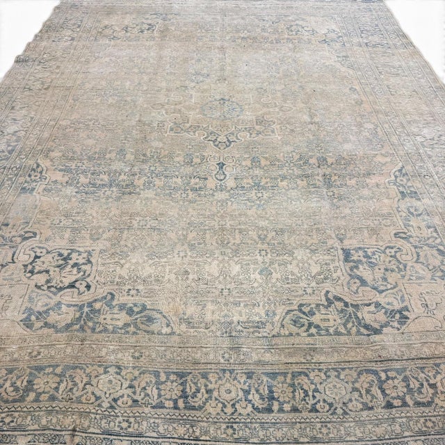 This elegant antique rug combines a refined blue and ivory palette with a richly detailed composition of delicate floral...
