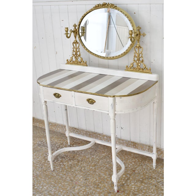 A dressing table of elegant neoclassical design, comprising a table with curved lines and a folding oval mirror. The...