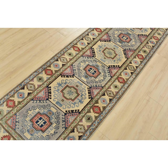 A tribal Caucasian Kazak runner hand-knotted with fine wool on a cotton foundation. This rug features a row of geometric...