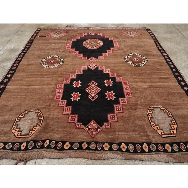 This piece features a wool pile of symmetric knots on a wool foundation. The abrashed medium brown field displays two...