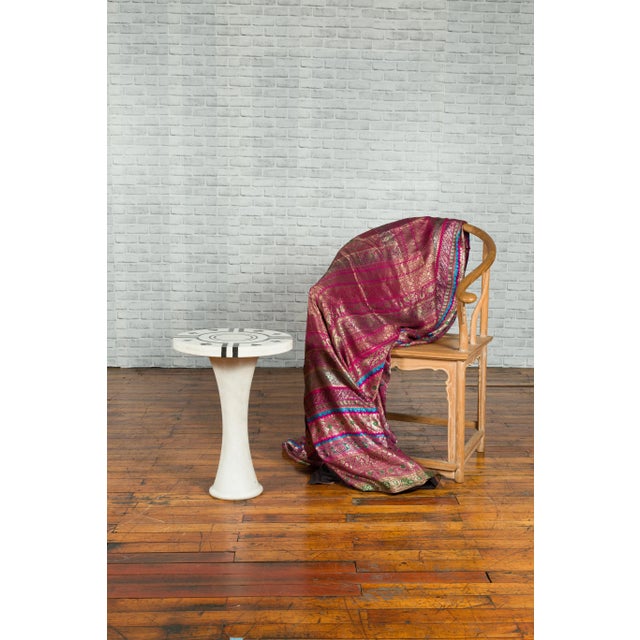 A white marble side table from the 20th century, with circular poker design top and pedestal base. Showcasing one of our...