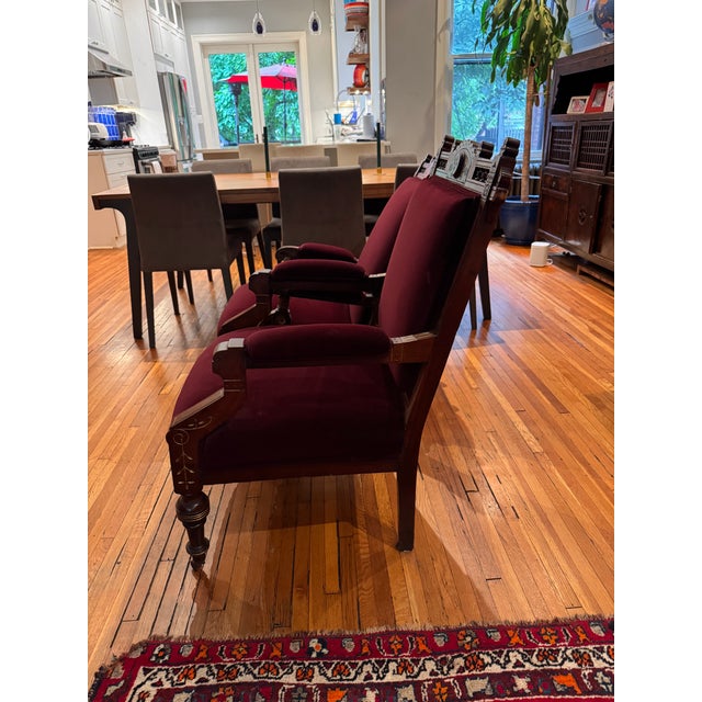 A stunning pair of American Eastlake parlor chairs, circa 1870s–1880s, featuring exquisite carved walnut crestwork, gold...