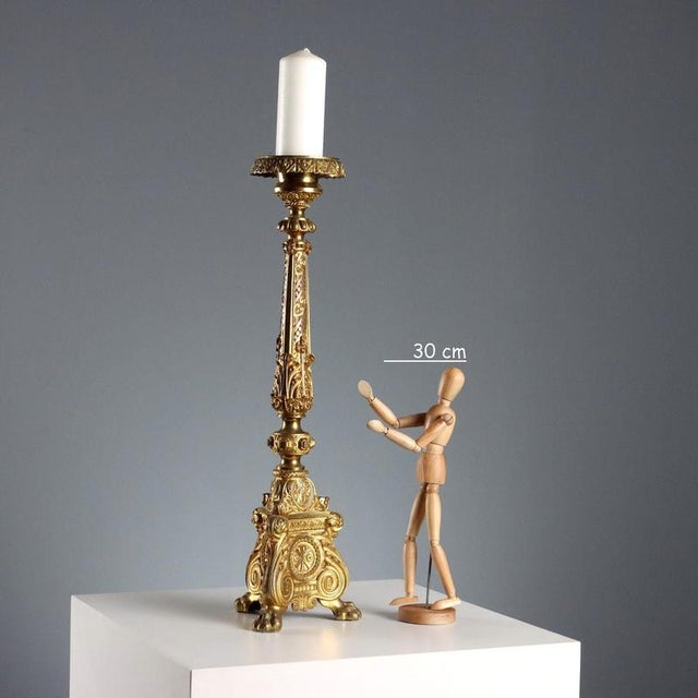 A gilded and chiseled bronze torch holder with a triangular base, supported by three feline paws. Decorated with leafy...