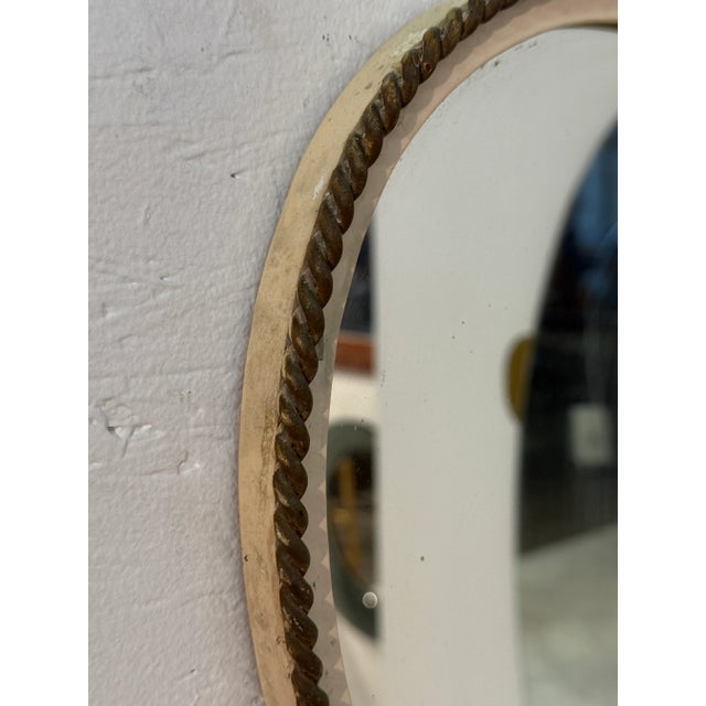A unique Italian mid-century wall mirror featuring an organic, freeform shape framed with a rope-style trim. Its fluid...