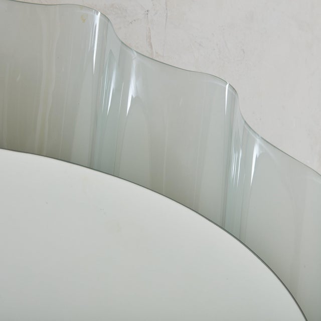 A rare Italian ‘Onda’ wall mirror designed by Nanda Vigo for Glas Italia in the 1980s. The oval mirror glass gracefully...