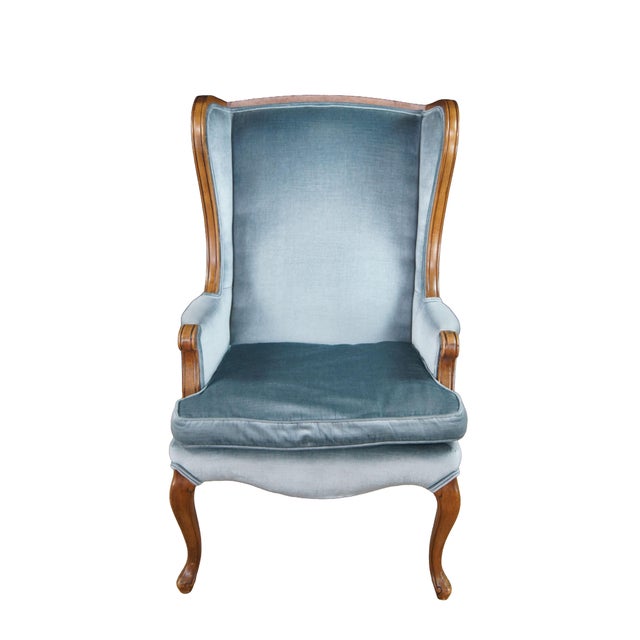 Vintage Queen Anne Style Wingback Chair. Features a distressed wood frame and blue velvet upholstery. The wingback chair...