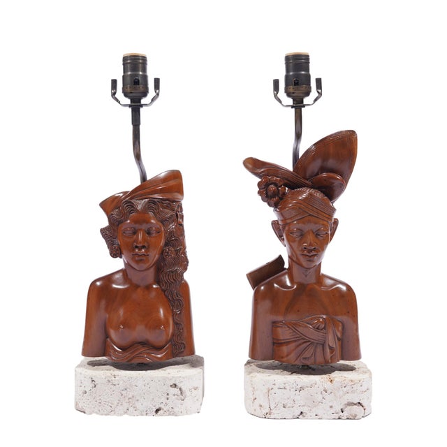 A pair of Balinese carved hardwood bust lamps, circa 1920-1940, depicting a man and a woman in formal traditional dress....
