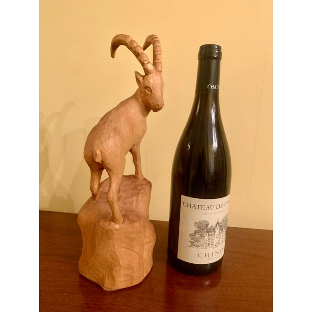 Available is an antique early / mid-20th century wooden carved sculpture of an ibex standing atop a rocky alpine...