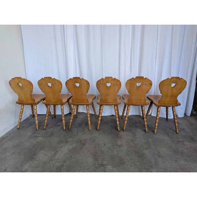 Set of 8 vintage wooden dining chairs in Tyrolean style. The chairs feature solid wooden construction with bobbin-turned...