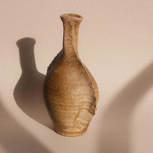 A sculptural vase in patinated stoneware with delicate pink reflections, made in Puisaye. Its wing-like fluted contours...