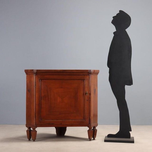 Directoire cherry corner cabinet from Emilia, dating back to the early 19th century. The structure features a central...