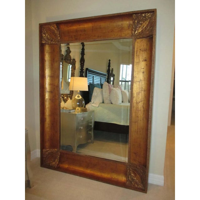Beveled floor mirror featuring a wood frame with carved leaves and berries on each corner and a bronze finish. Hardware on...