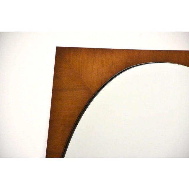 A mid century modern oval mirror with a square frame. Walnut color finish