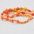 This colorful extra-long Bakelite and Lucite necklace features assorted beads in various carved shapes: round, tomato, and...