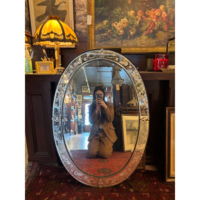 Elegant early 20th-century Venetian oval mirror featuring an ornate mirrored-glass frame beautifully etched with scrolling...