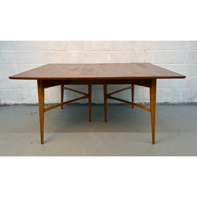 A beautifully crafted mid-century modern walnut dining table featuring a clean, timeless silhouette and a functional...