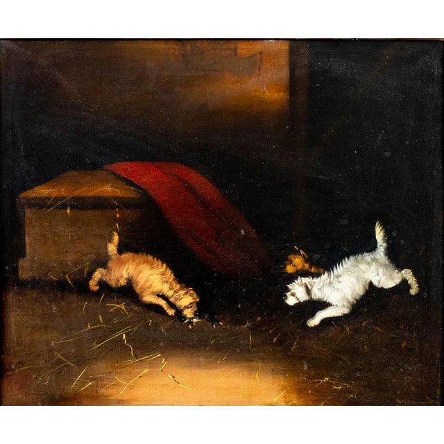 A charming 19th-century British oil painting depicting three energetic dogs in a stable interior. The warm light, deep...