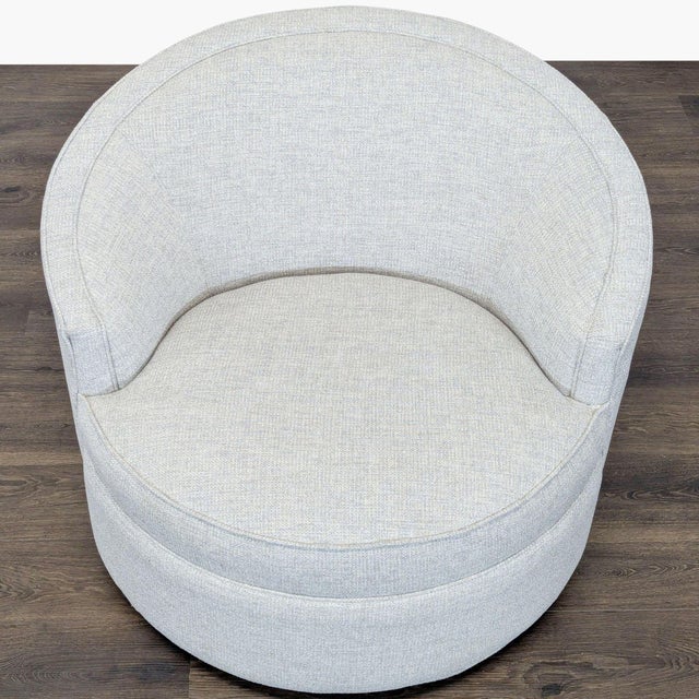 This modern lounge chair features a sleek, rounded design with a comfortable curved back and soft light gray fabric. Its...
