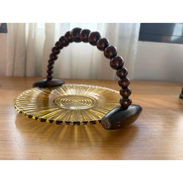 Sunburst ribbed amber glass with hand-gilded rings, finished with a beaded wooden swing handle on carved terminals....