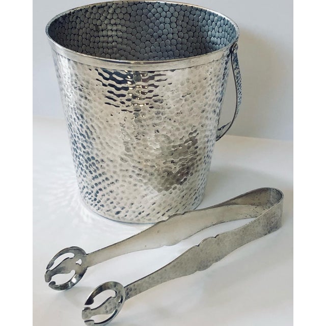 Arts & Crafts style in the tongs and hammered surfaces throughout, this stunning ice bucket looks great on any bar. Clean...