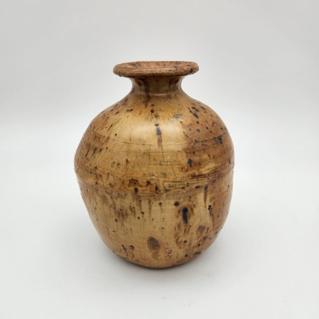 Hand-thrown stoneware bud vase with warm amber speckled glaze, flared lip, bulbous body, and signed base