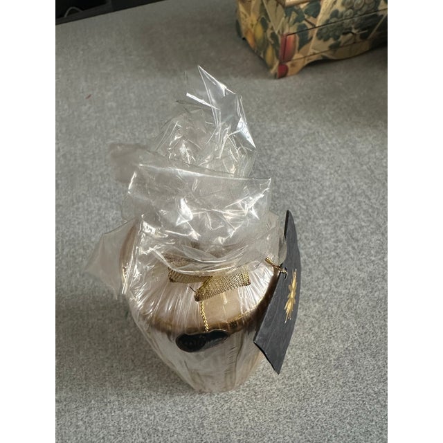 A decorative candle from Velas Artisticas, featuring a gold finish and part of The Italian Collection. It is wrapped in...