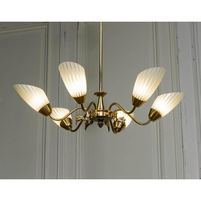 This is a Swedish brass chandelier from the 1950s, featuring six elegantly curved arms with floral decorations. Each arm...