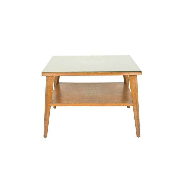 This square coffee table is made from a teak wood structure with a green glass top. It feautures a doble usefull shelves....