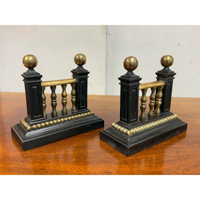 Design Plus Gallery presents a Pair of Fire Dogs of Antique Age. They are heavy and made from cast iron with brass tops....