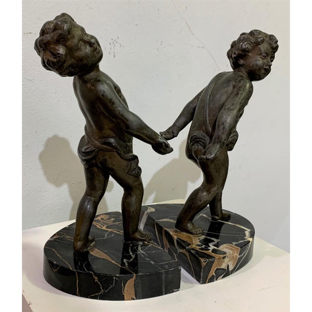 Pair of bookends. Metal alloy cushions on marble with bronze artist's stamp on the base.