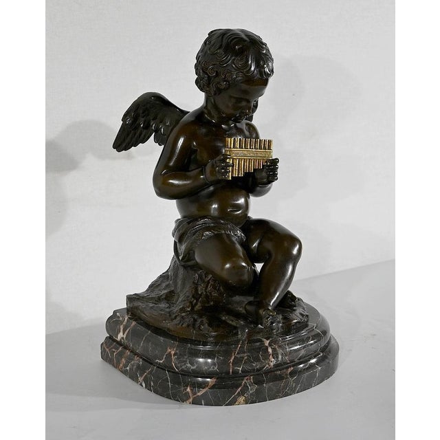 Charming bronze with black and golden patina, in the 18th century style, representing an angel holding a golden panpipes...