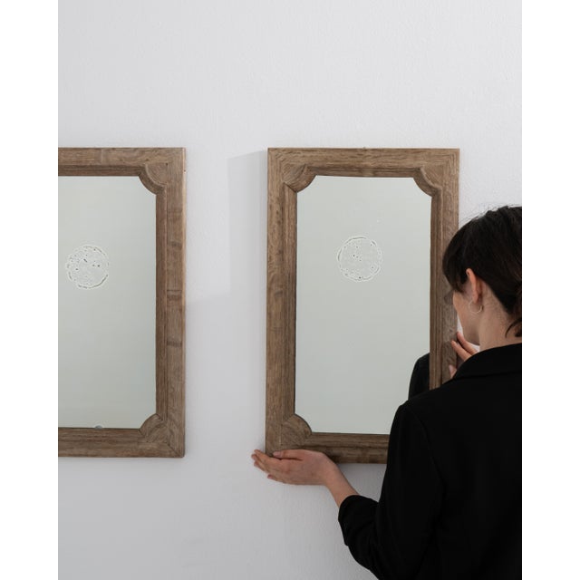 A pair of circa 1900 French wall mirrors crafted in oak, featuring a more compact format with a straightforward frame...