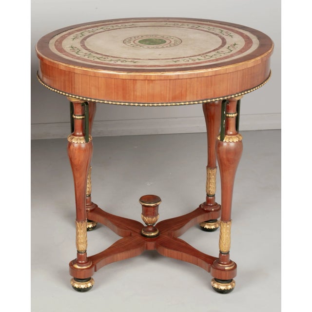 An Italian Neoclassical circular center table made of solid and veneer of cherry. The top is scagliola, a hand-painted...