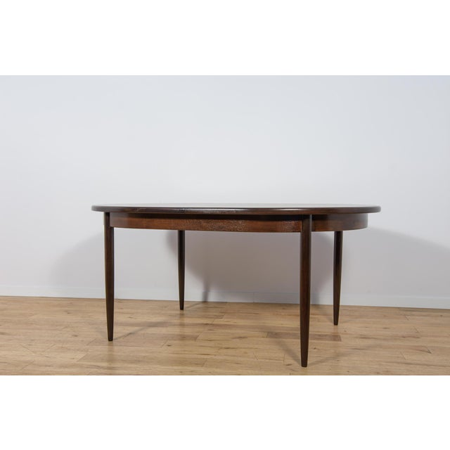 This is an oval-shaped teak dining table manufactured by G-Plan in the 1960s. The table has reinforced edges of the top....