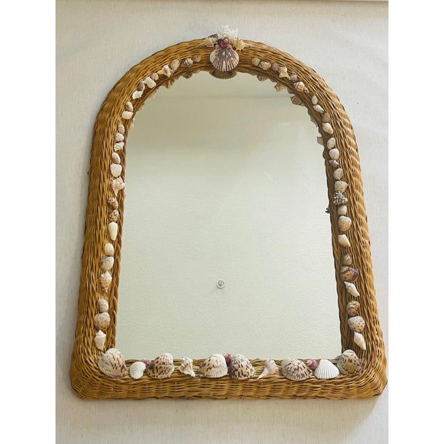 Mid century wicker wall mirror encrusted with sea shells as coastal decor.